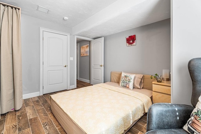 bedroom featuring wood finish floors, visible vents, and baseboards