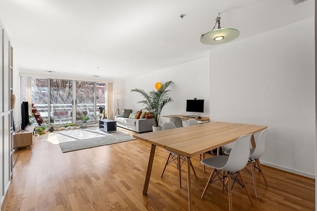 dining space featuring expansive windows and light hardwood / wood-style flooring