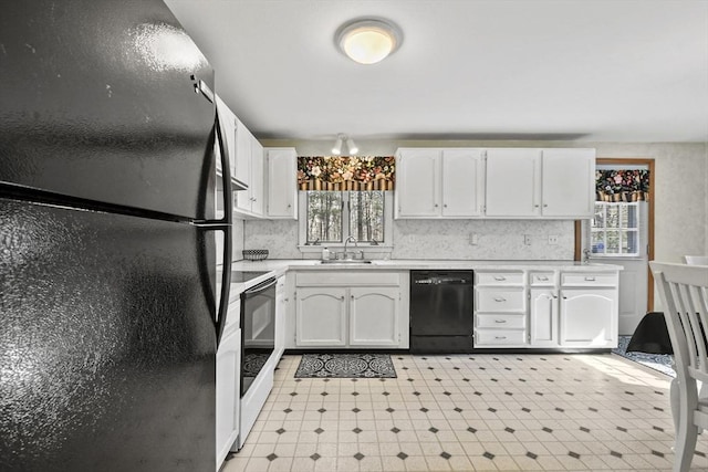 kitchen with light countertops, white cabinets, a sink, and black appliances