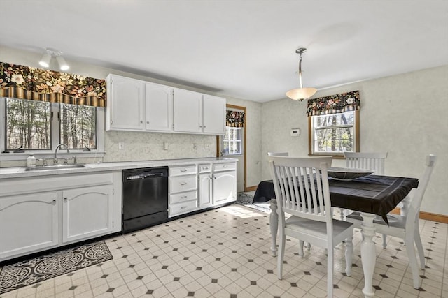 kitchen with light countertops, dishwasher, a sink, and white cabinetry