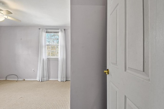 interior space featuring light carpet, a ceiling fan, and baseboards