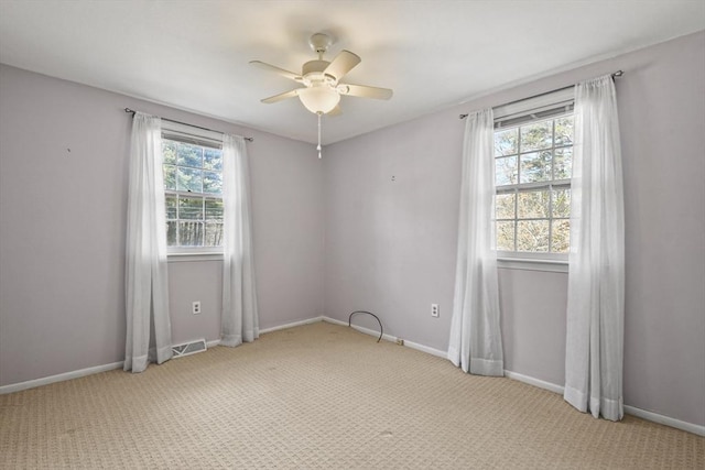 carpeted spare room featuring visible vents, a ceiling fan, and baseboards