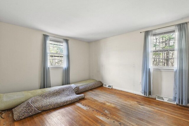 bedroom with hardwood / wood-style floors, visible vents, and baseboards