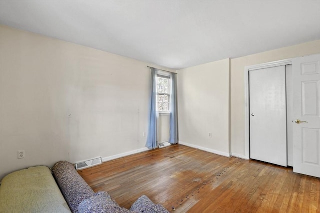 living area with visible vents, baseboards, and wood finished floors