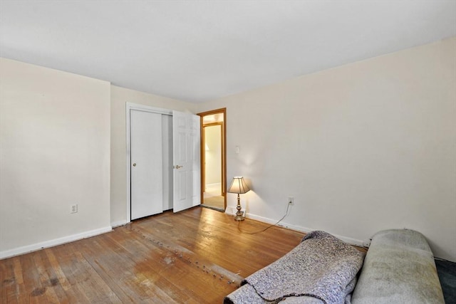 interior space featuring a closet, wood-type flooring, and baseboards