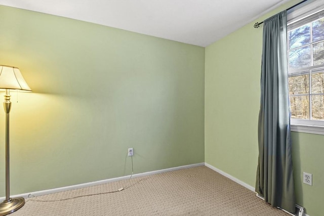 spare room with a healthy amount of sunlight, baseboards, and light colored carpet