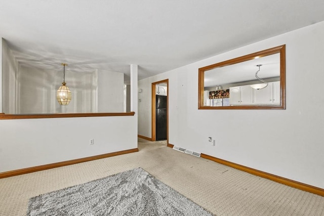 carpeted empty room featuring baseboards and visible vents