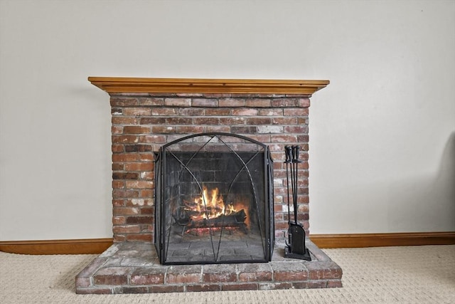 interior details featuring carpet floors, a brick fireplace, and baseboards