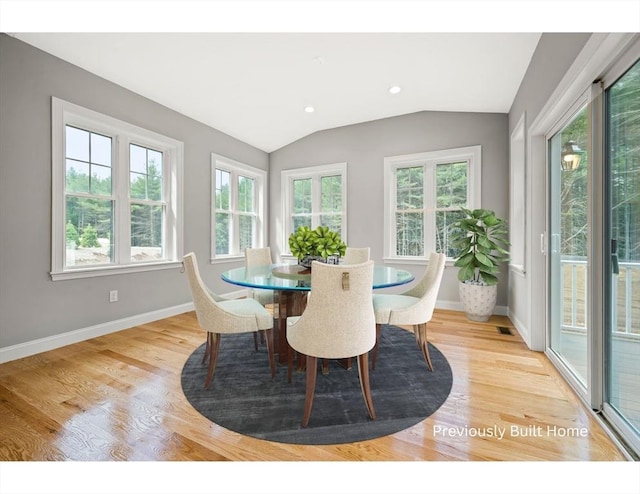 dining room featuring baseboards, light wood finished floors, and lofted ceiling