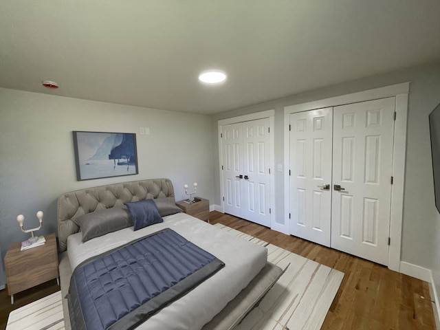 bedroom featuring multiple closets and hardwood / wood-style floors