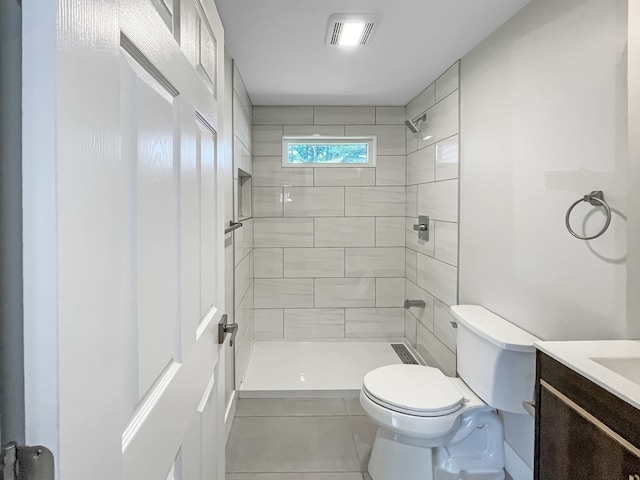 bathroom with tile patterned flooring, tiled shower, vanity, and toilet