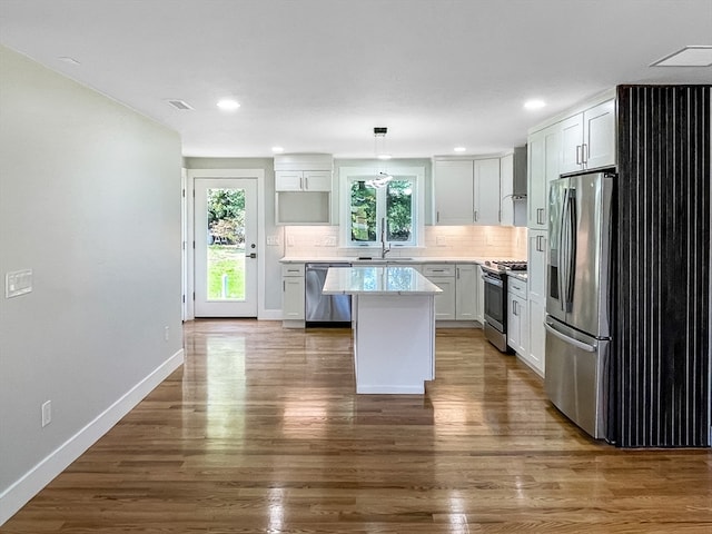 kitchen with a kitchen island, dark wood-type flooring, decorative light fixtures, appliances with stainless steel finishes, and white cabinetry