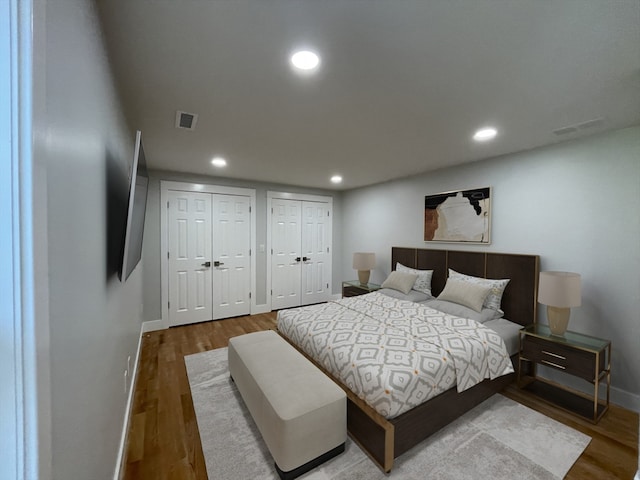 bedroom with multiple closets and hardwood / wood-style floors