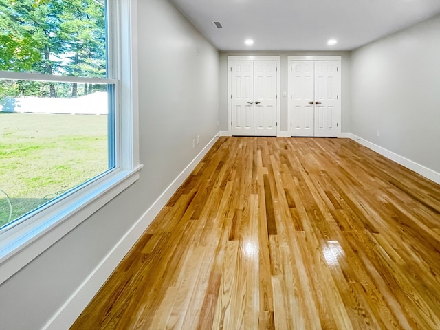 unfurnished bedroom featuring light hardwood / wood-style floors and two closets