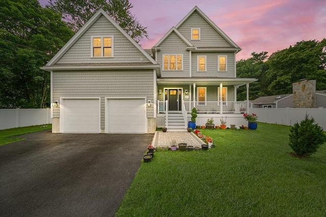 view of front facade featuring a garage, a lawn, and covered porch