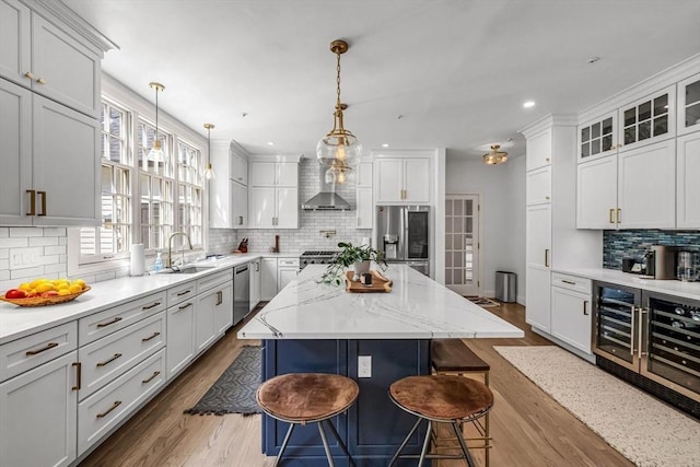 1 Webster Ln, Wilbraham, MA 01095 - kitchen featuring wall chimney range hood, a sink, stainless steel appliances, decorative backsplash, and a kitchen bar