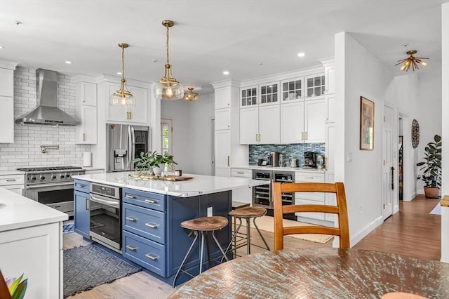 1 Webster Ln, Wilbraham, MA 01095 - kitchen featuring appliances with stainless steel finishes, wall chimney exhaust hood, blue cabinets, white cabinets, and wine cooler