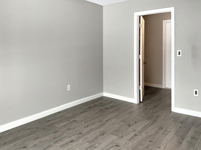 spare room with dark wood-style floors and baseboards