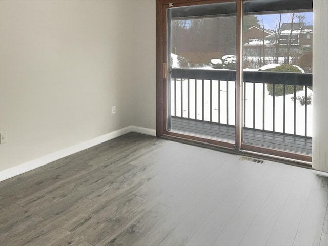 unfurnished room with visible vents, plenty of natural light, baseboards, and wood finished floors