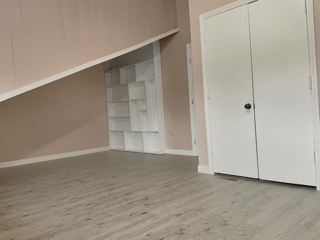 unfurnished bedroom featuring baseboards, a closet, and light wood-style floors