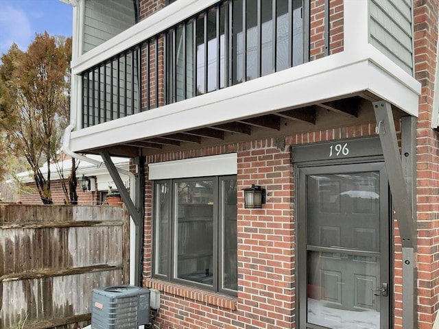 doorway to property with central AC unit and brick siding