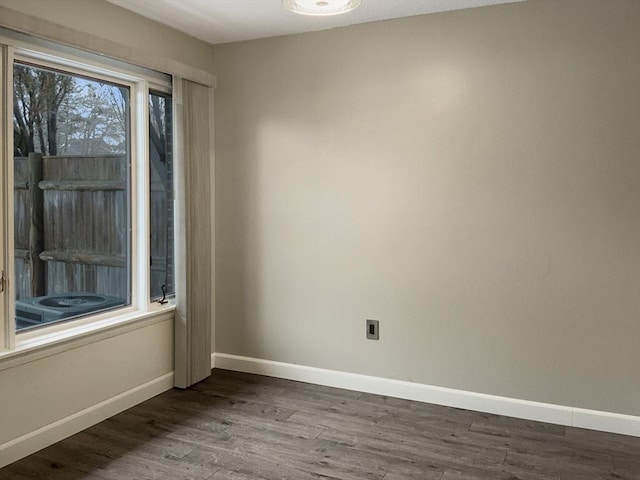 spare room with baseboards and wood finished floors