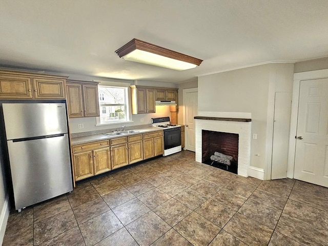 kitchen featuring under cabinet range hood, light countertops, range with gas stovetop, freestanding refrigerator, and a sink