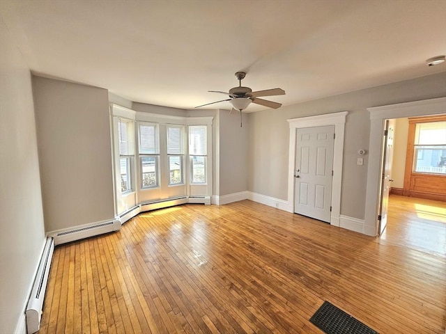 unfurnished room featuring a baseboard radiator, baseboards, visible vents, and light wood-style flooring