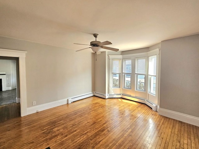 empty room featuring a brick fireplace, baseboards, wood-type flooring, and ceiling fan