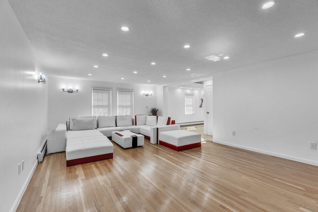 living room with a baseboard radiator, light wood-type flooring, and a textured ceiling