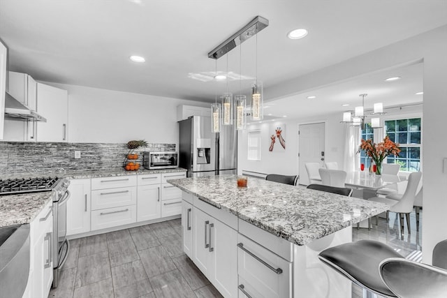 kitchen featuring a kitchen island, appliances with stainless steel finishes, a breakfast bar, and white cabinetry