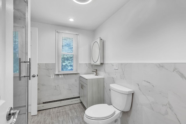 bathroom featuring tile walls, baseboard heating, vanity, and toilet