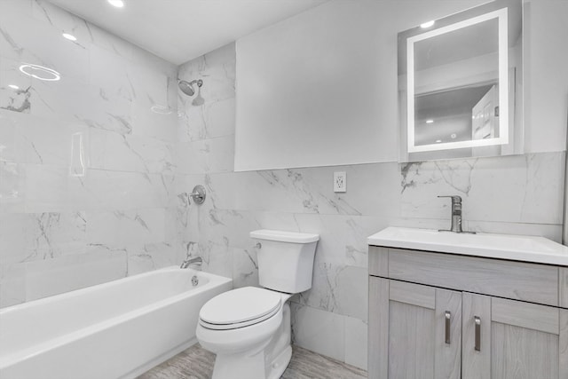 full bathroom featuring tile walls, tiled shower / bath combo, vanity, and toilet