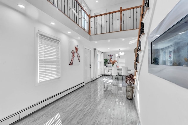 foyer entrance with a baseboard radiator, a towering ceiling, and a healthy amount of sunlight