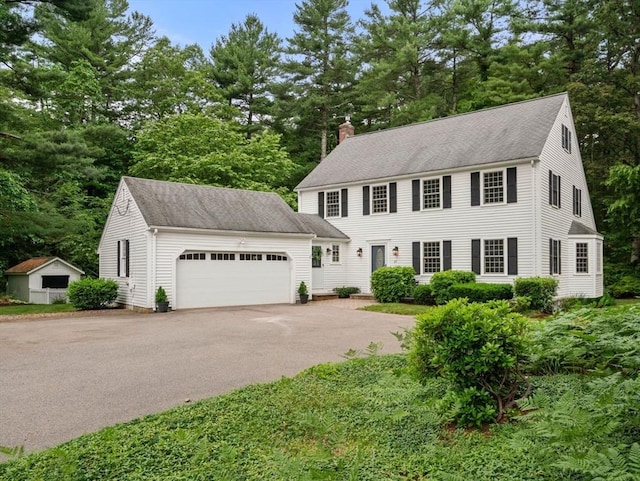 23 Lafayette Dr, Walpole, MA 02032 - colonial-style house featuring a chimney, asphalt driveway, an attached garage, view of scattered trees, and roof with shingles