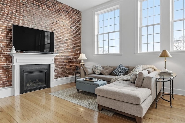 living room with plenty of natural light, brick wall, and light wood-type flooring