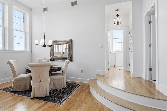 dining area with hardwood / wood-style flooring, plenty of natural light, and a notable chandelier