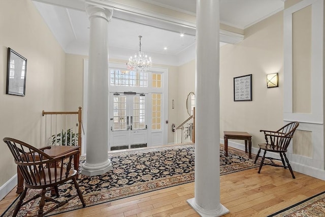 entryway with light wood-type flooring, crown molding, a high ceiling, and a chandelier