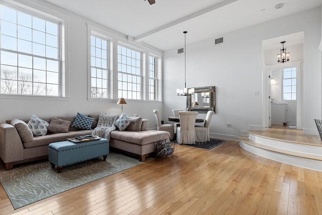 living room with a healthy amount of sunlight, wood-type flooring, and an inviting chandelier