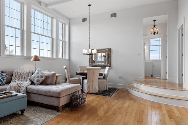 sitting room with hardwood / wood-style floors, a notable chandelier, and beamed ceiling