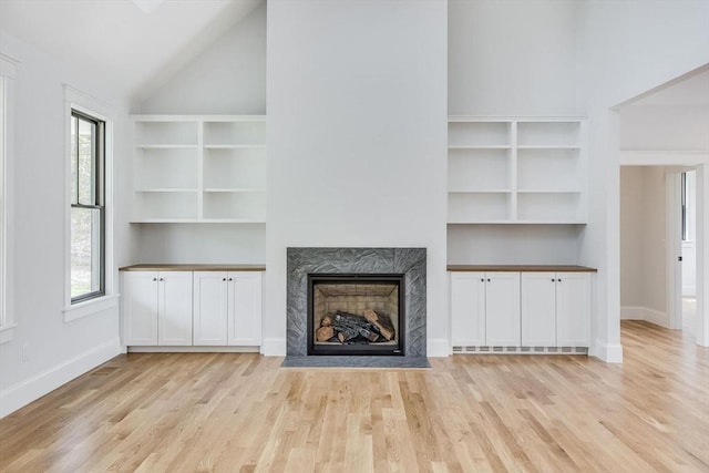 92 Whiffletree Ave, Brewster, MA 02631 - unfurnished living room with light wood-style floors, a premium fireplace, baseboards, and high vaulted ceiling