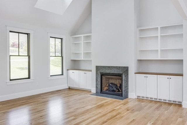92 Whiffletree Ave, Brewster, MA 02631 - unfurnished living room with light wood-style floors, a high end fireplace, high vaulted ceiling, a skylight, and baseboards