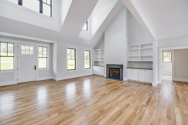 92 Whiffletree Ave, Brewster, MA 02631 - unfurnished living room featuring high vaulted ceiling, baseboards, a premium fireplace, built in shelves, and light wood-style floors