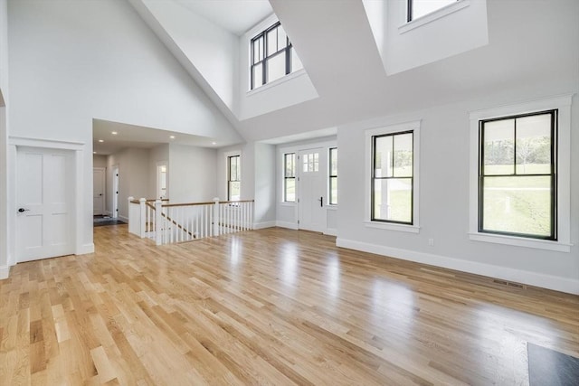 92 Whiffletree Ave, Brewster, MA 02631 - unfurnished living room with a towering ceiling, healthy amount of natural light, light wood finished floors, and baseboards