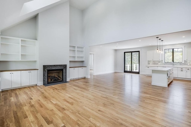 92 Whiffletree Ave, Brewster, MA 02631 - unfurnished living room featuring a towering ceiling, a high end fireplace, light wood-type flooring, recessed lighting, and built in features