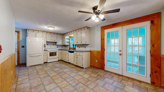 kitchen with wooden walls, under cabinet range hood, white appliances, french doors, and wainscoting