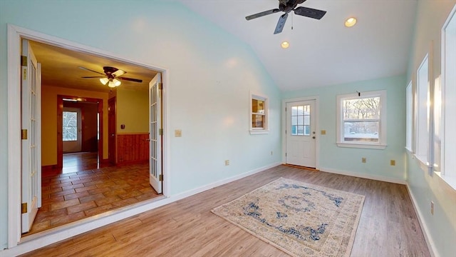 foyer entrance with a wealth of natural light, lofted ceiling, baseboards, and wood finished floors