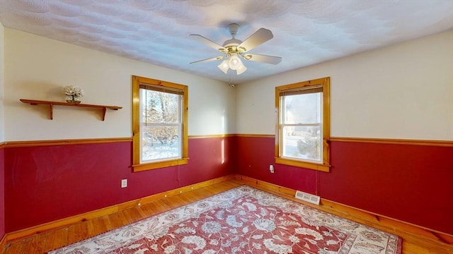 unfurnished room featuring plenty of natural light, wood finished floors, and visible vents