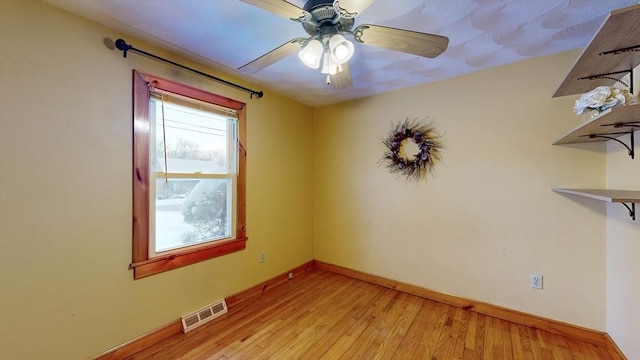 empty room featuring light wood finished floors, baseboards, visible vents, and ceiling fan