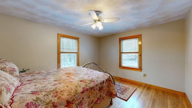 bedroom with wood-type flooring, baseboards, and a ceiling fan